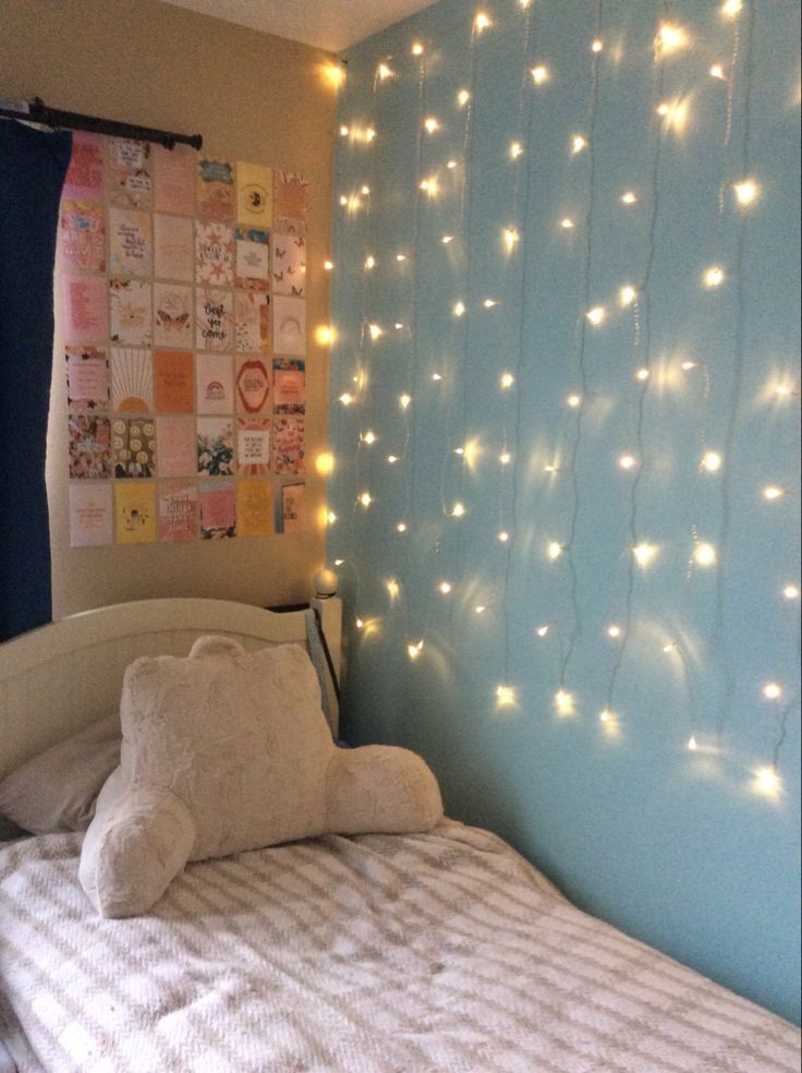 a bed room with a neatly made bed and string lights on the wall above it