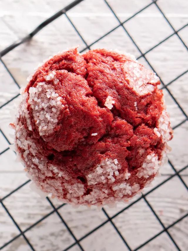 a red cookie is sitting on a cooling rack