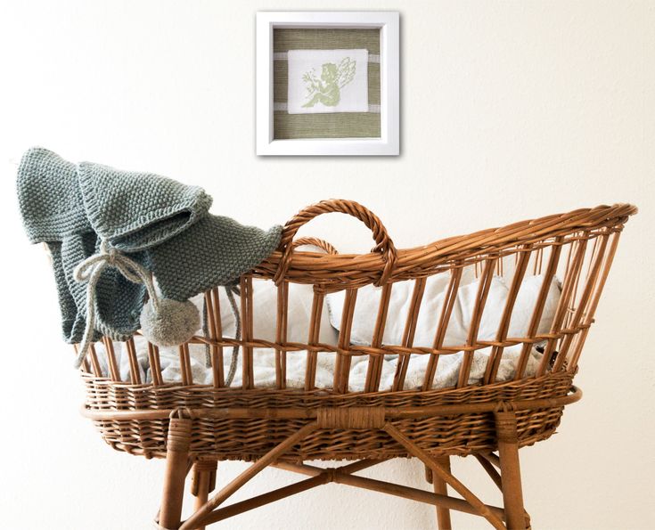 a baby's crib with a blanket and hat on it next to a wall