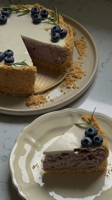 two plates with slices of cheesecake and blueberries on them