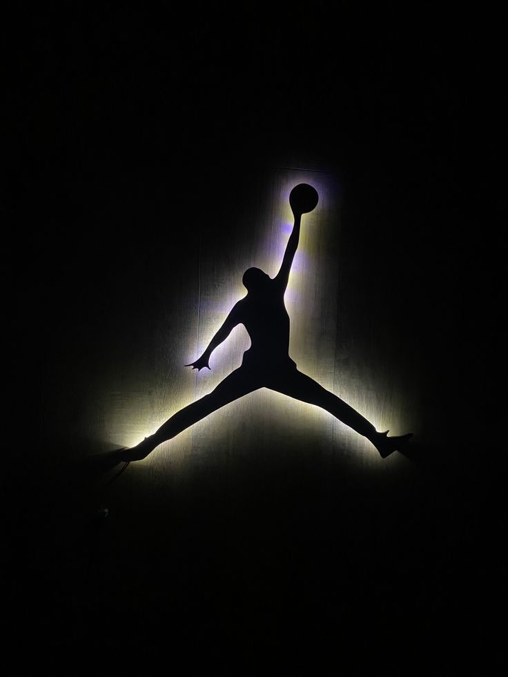 the silhouette of a basketball player jumping in the air with his arms outstretched, holding a ball