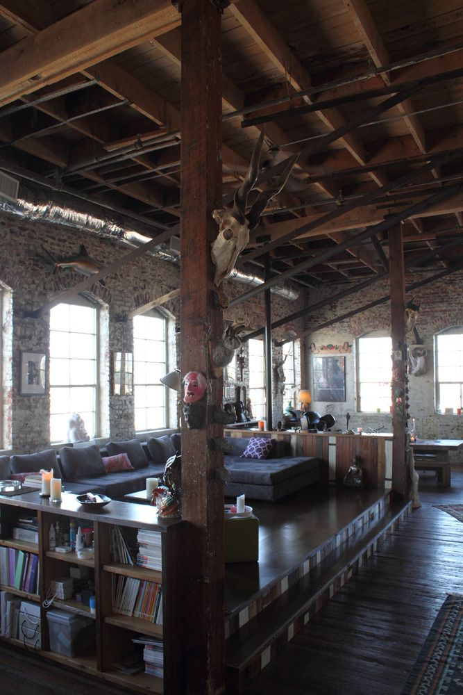 a living room filled with lots of furniture next to tall windows and wooden beams on the ceiling