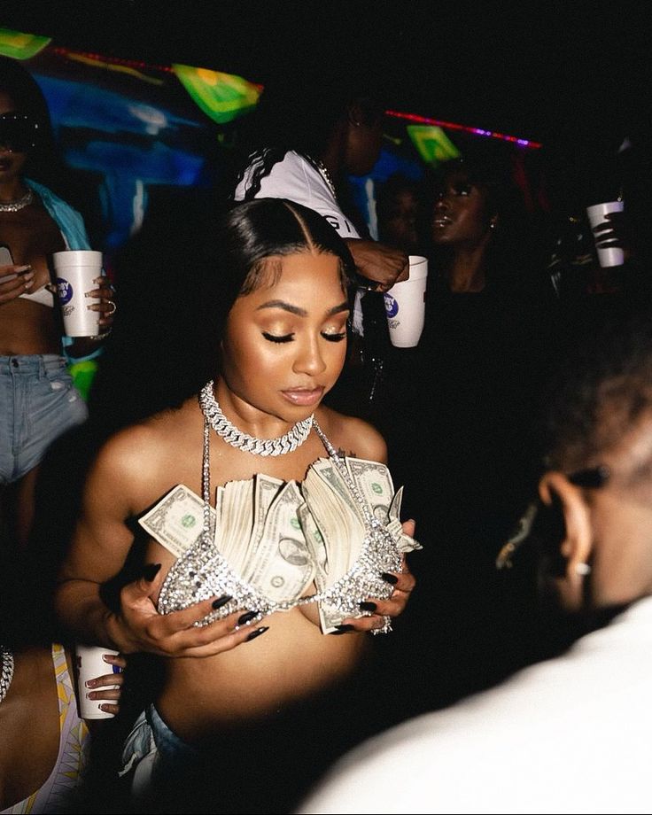 a woman holding money in her hands while standing next to other people at a party