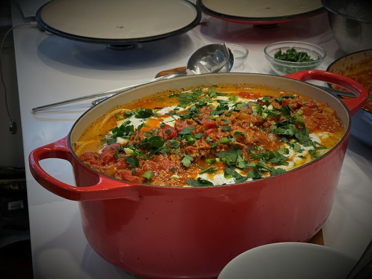 a red pot filled with food sitting on top of a counter next to other dishes