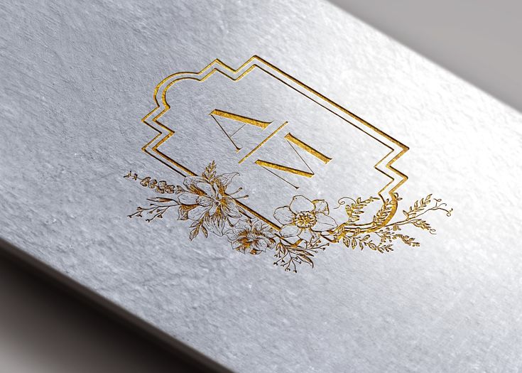 a silver and gold foiled business card with an elegant floral design on the front