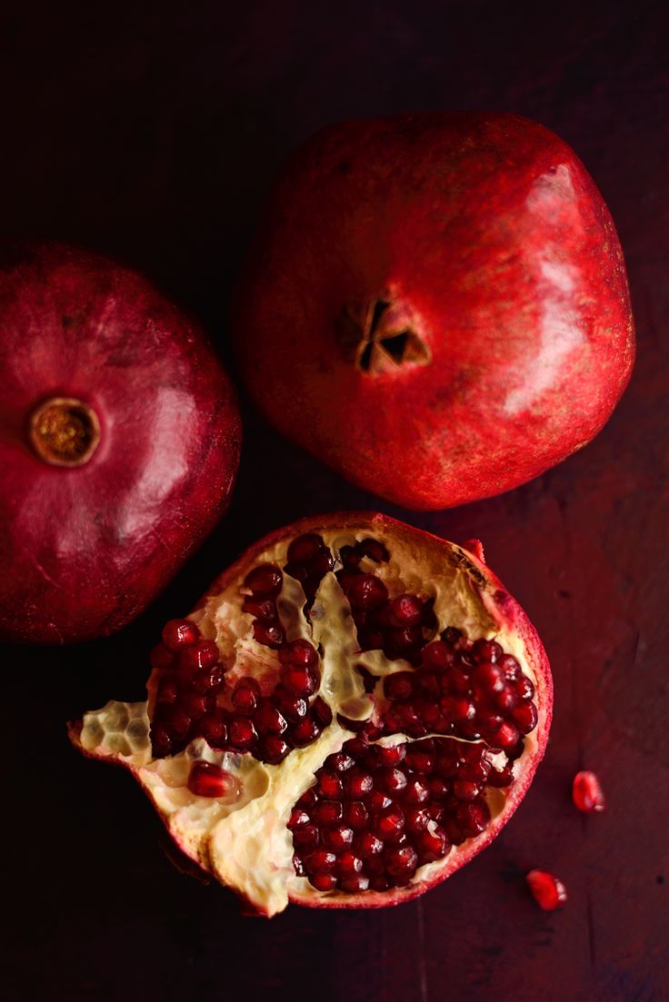 two pomegranates on a table with one cut in half