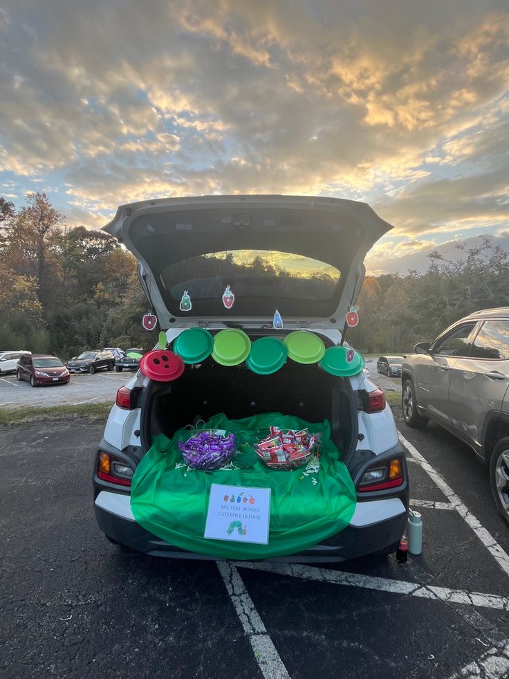 the back end of a car with its trunk open and decorations on it's hood