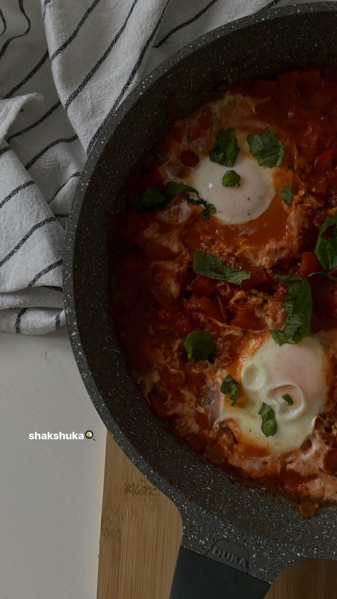 a pot filled with meat and sauce on top of a wooden table next to a towel