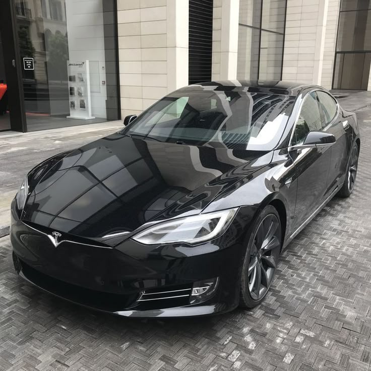 a black tesla parked on the side of a street