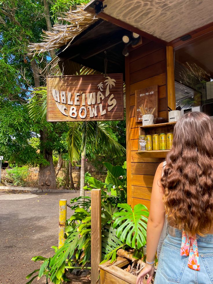 wooden Haleiwa Bowls shack surrounded by bright green leaves and a woman standing to the right ordering a smoothie North Shore Aesthetic, Hawaii College Aesthetic, College In Hawaii, Living In Hawaii Aesthetic, Oahu Aesthetic, Hawaii Pacific University, Lihue Hawaii, North Shore Hawaii, Hawaii Aesthetic