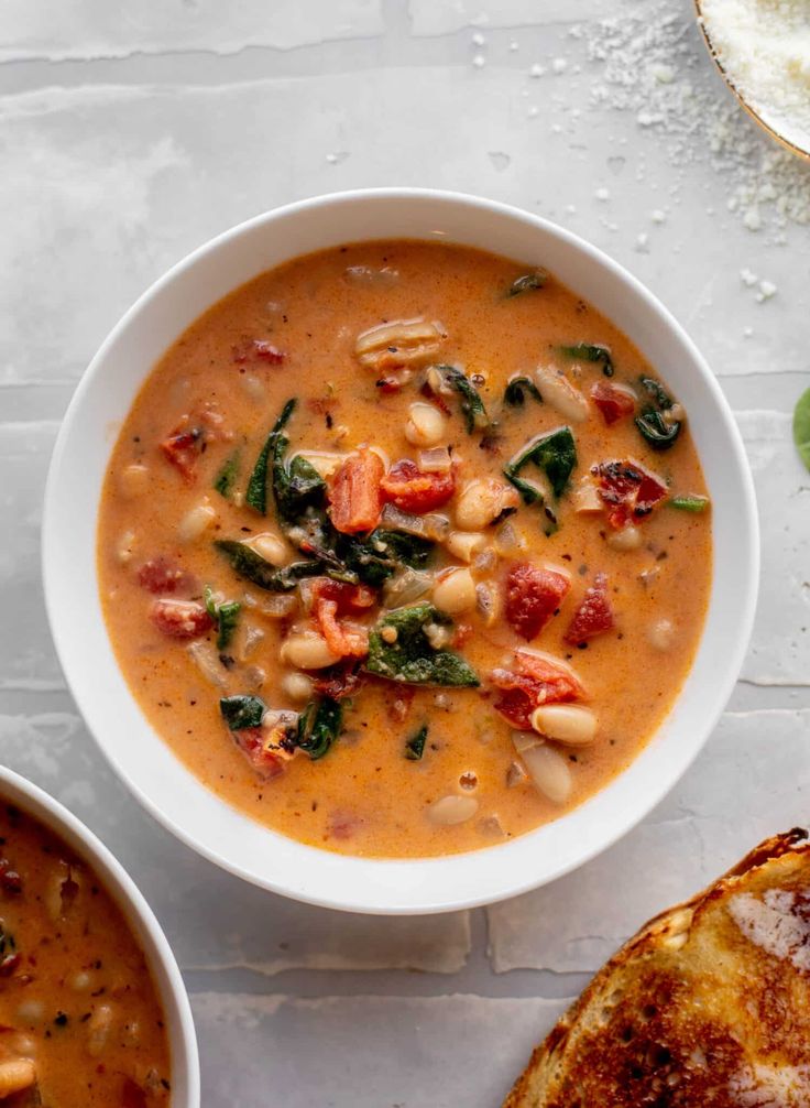 two bowls of soup on a table with bread