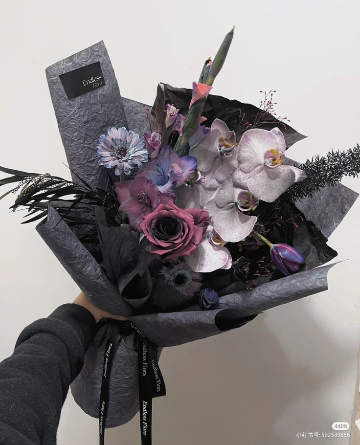 a person holding a bouquet of flowers in their hand with the tag attached to it