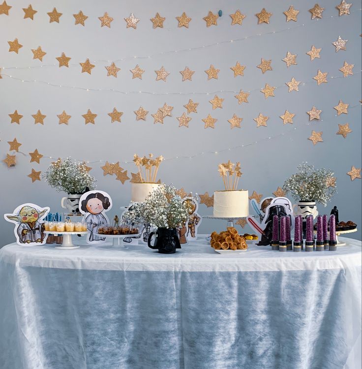 a table topped with lots of food and desserts next to a wall covered in stars