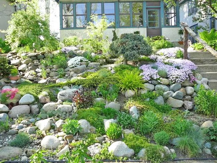 a house with lots of rocks and plants on the front lawn, along with steps leading up to it