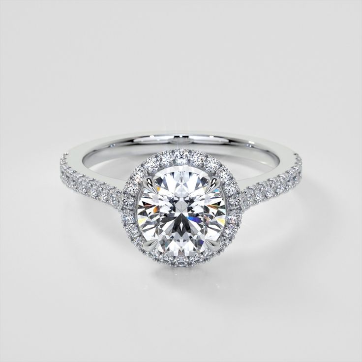 a white gold engagement ring with an oval halo setting and pave diamonds on the band