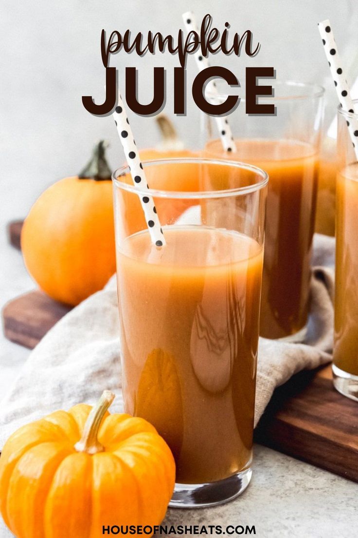 three glasses filled with liquid sitting on top of a wooden cutting board next to pumpkins