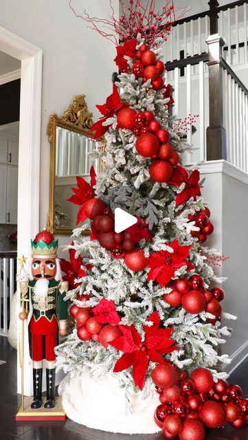 a christmas tree decorated with red and white ornaments in a living room next to stairs