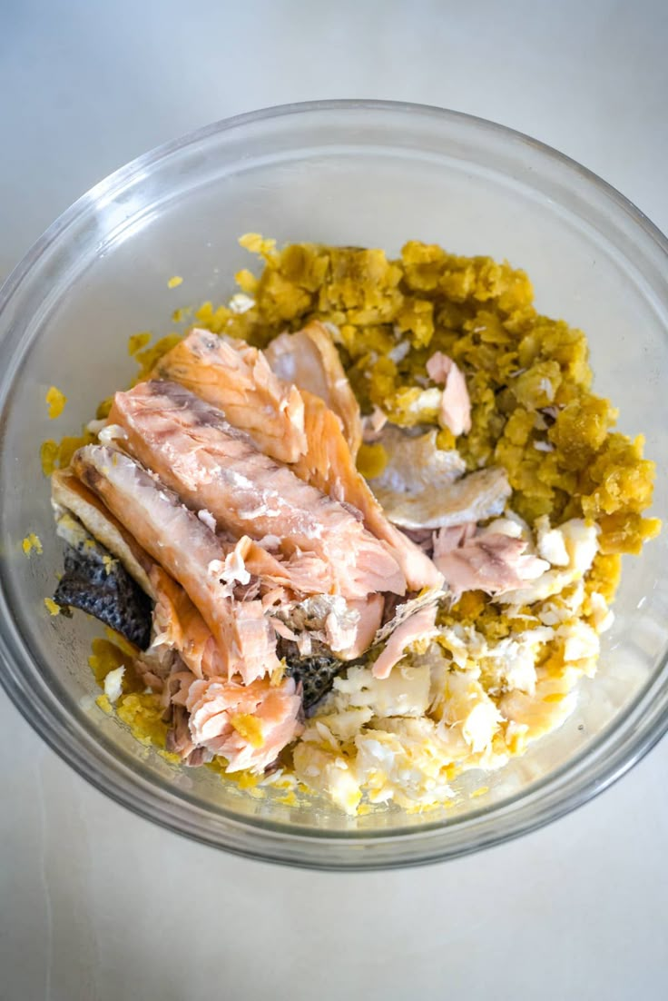 a glass bowl filled with food on top of a white countertop next to a knife and fork