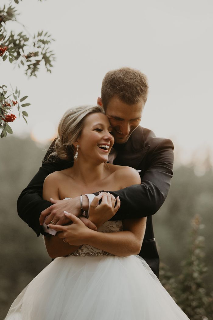 a bride and groom hugging each other outside