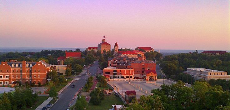 an aerial view of a city at sunset with cars parked on the street and buildings in the background