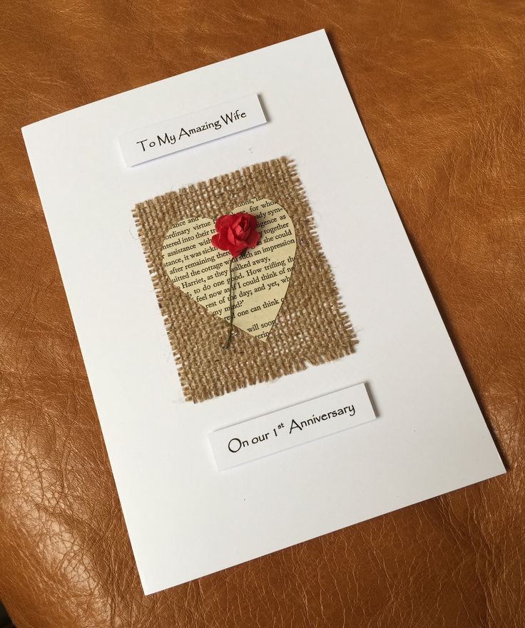 a piece of paper with a red rose pinned to it on top of a card