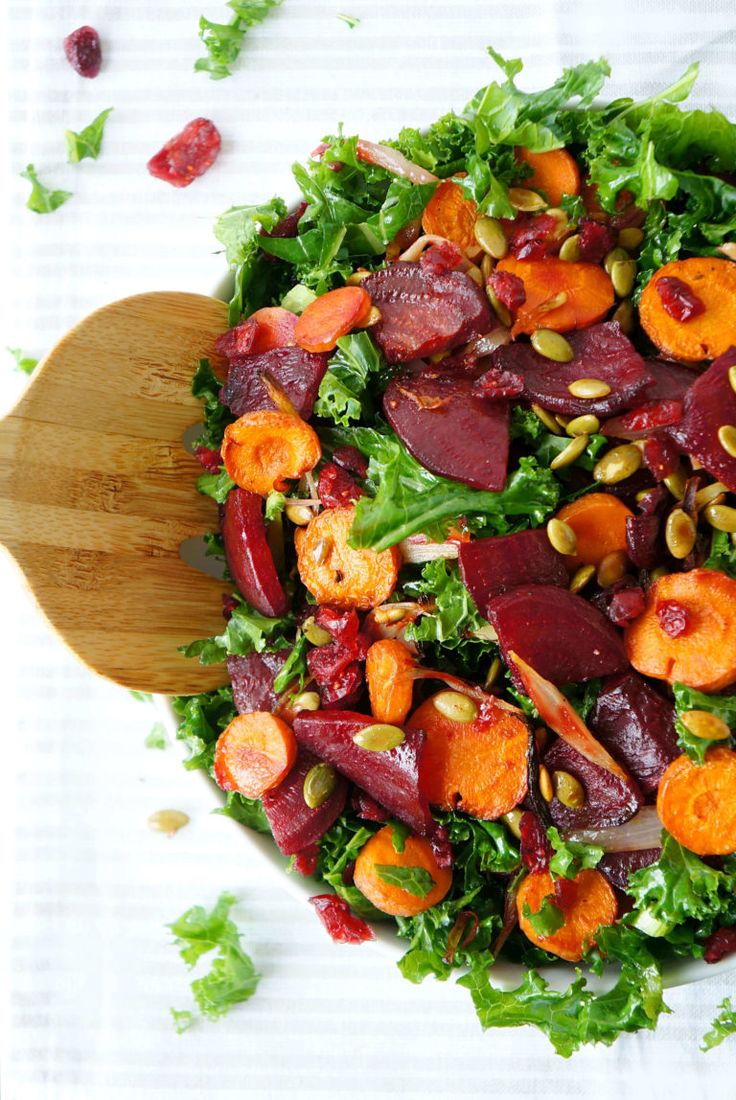 a salad with beets, carrots and pistachio seeds on a wooden spoon