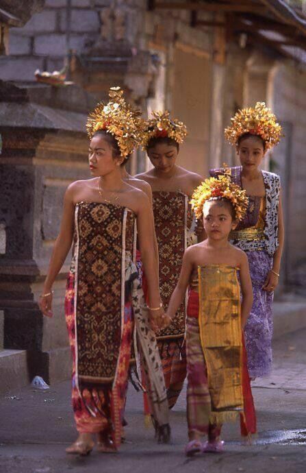 three women and two children walking down the street in traditional thai garb, holding hands with each other