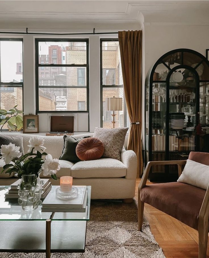 a living room filled with furniture and windows next to a tall window covered in bookshelves