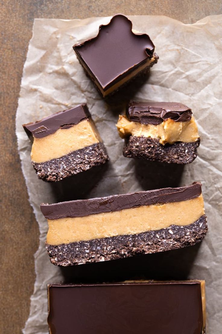 four pieces of chocolate and peanut butter bars on wax paper with one slice cut in half