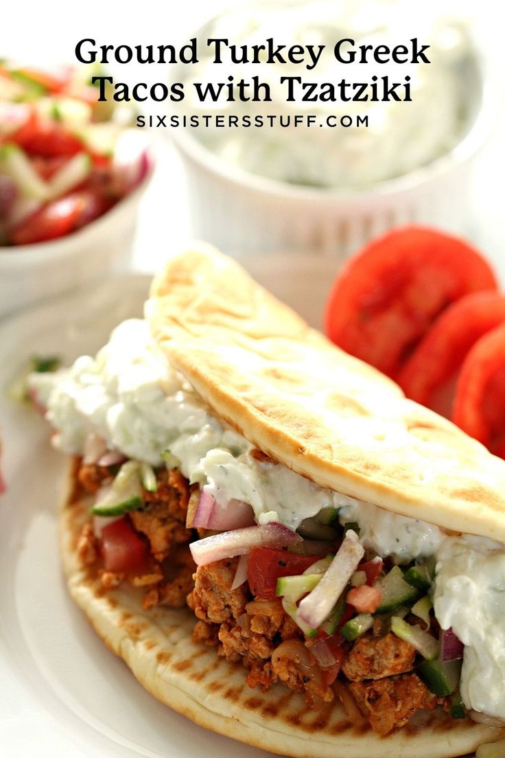 a close up of a pita sandwich on a plate with tomatoes in the background