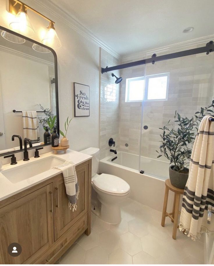 a bathroom with a sink, toilet and bathtub next to a shower curtain that has plants on it