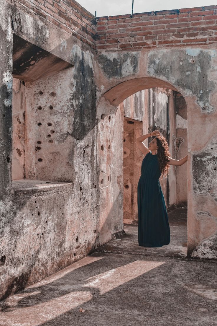 a woman standing in an old building with her hair blowing in the wind and wearing a black dress