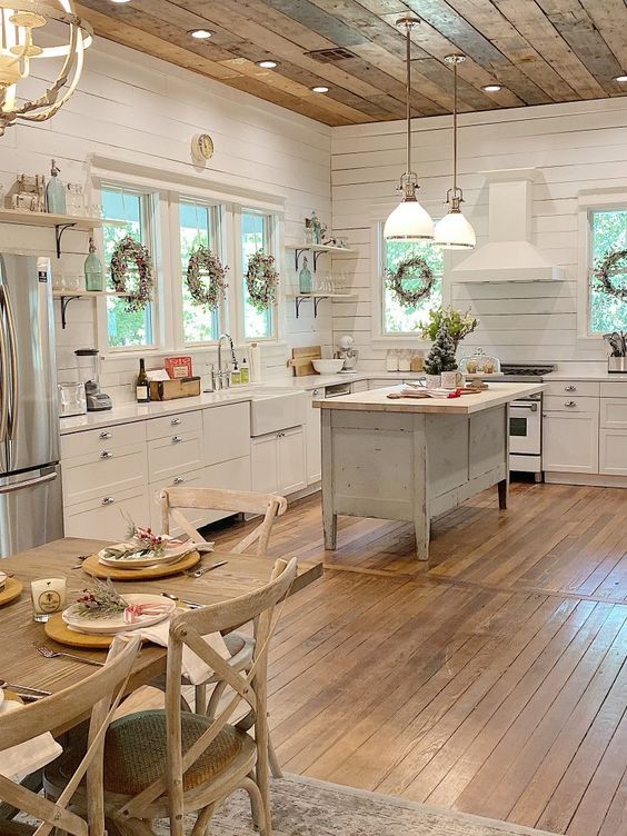 a kitchen with white cabinets and wood floors has an arrow pointing to the center island