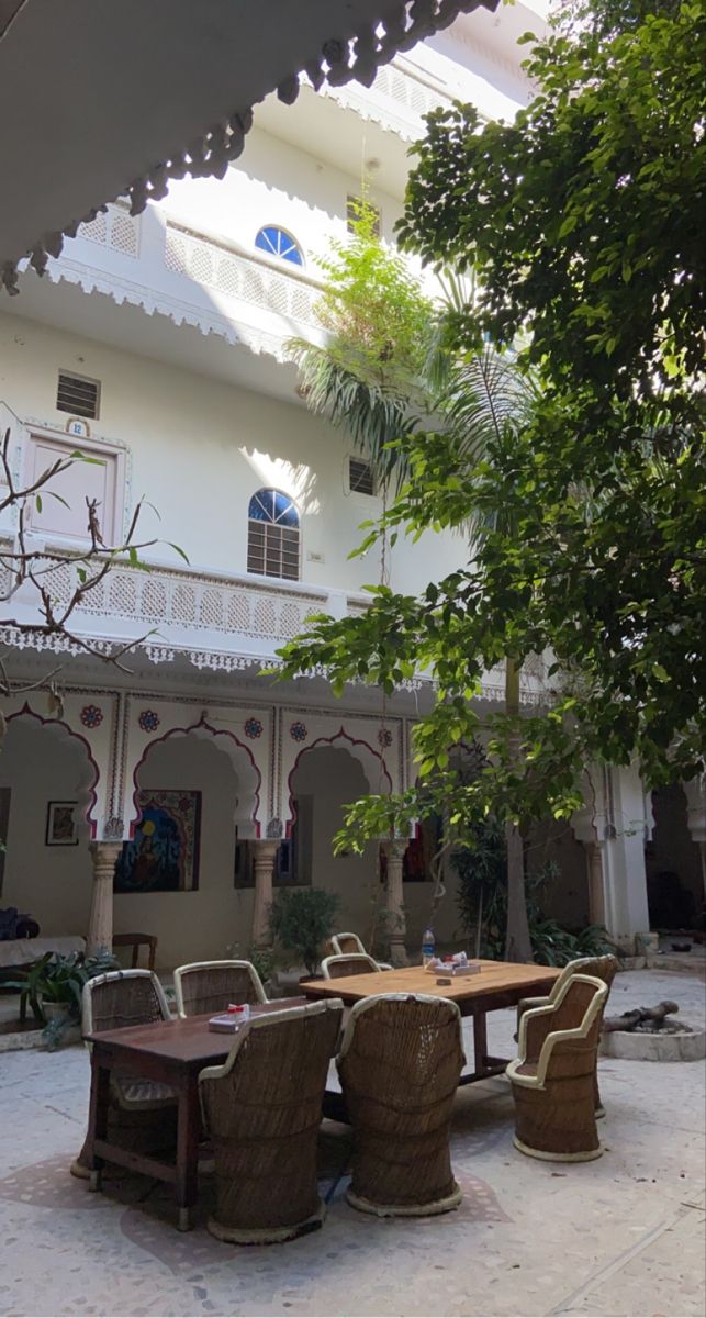 an outdoor dining area with wicker chairs and tables in front of a white building