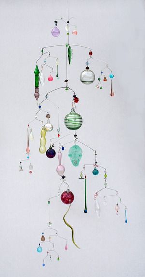 a wind chime with ornaments hanging from it's sides on a white wall