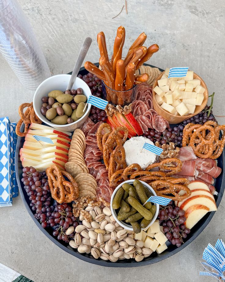 a platter filled with meats, cheeses, crackers and pretzels