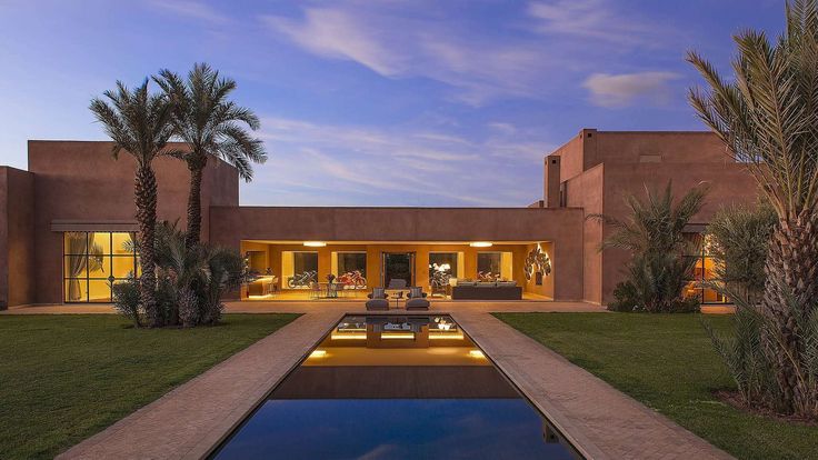 a house with a pool in front of it and palm trees around the pool area