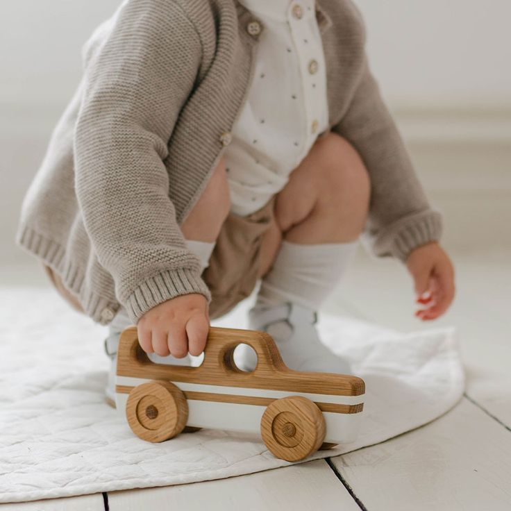 a baby playing with a wooden toy truck