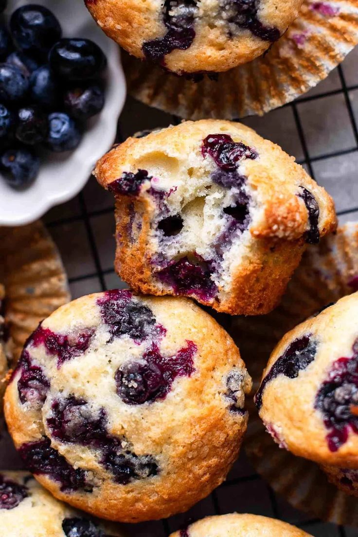 blueberry muffins on a cooling rack with fresh blueberries in the background