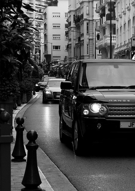 black and white photograph of cars driving down the street