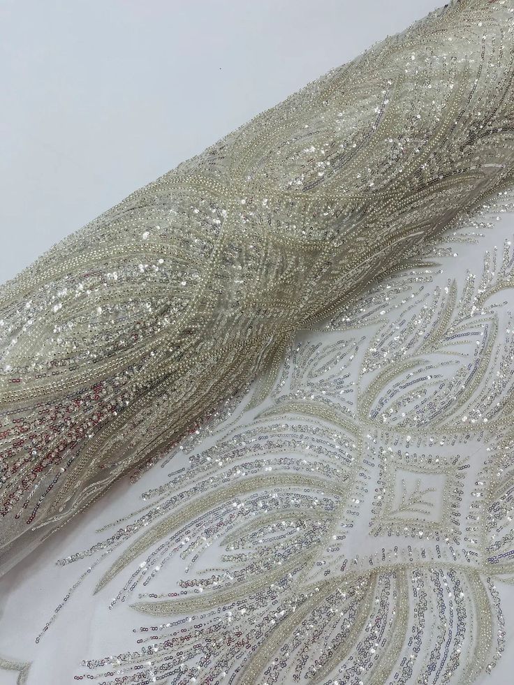 the fabric is shiny and has silver sequins on it, along with an intricate design