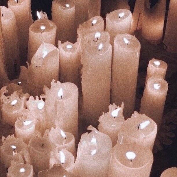 many lit candles are lined up in rows