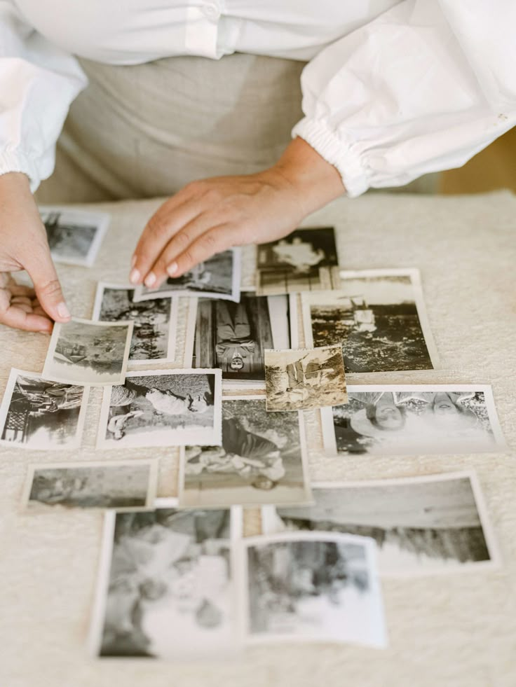 a woman is placing pictures on the table with her hands in front of them,