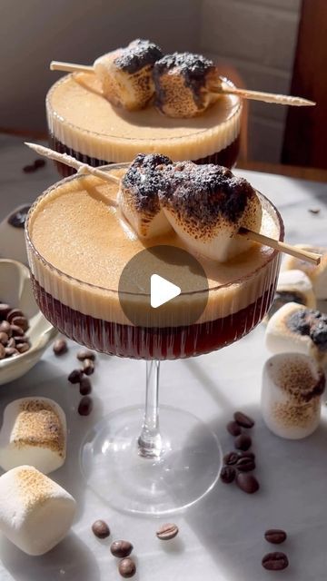 two desserts sitting on top of a table with marshmallows and coffee beans