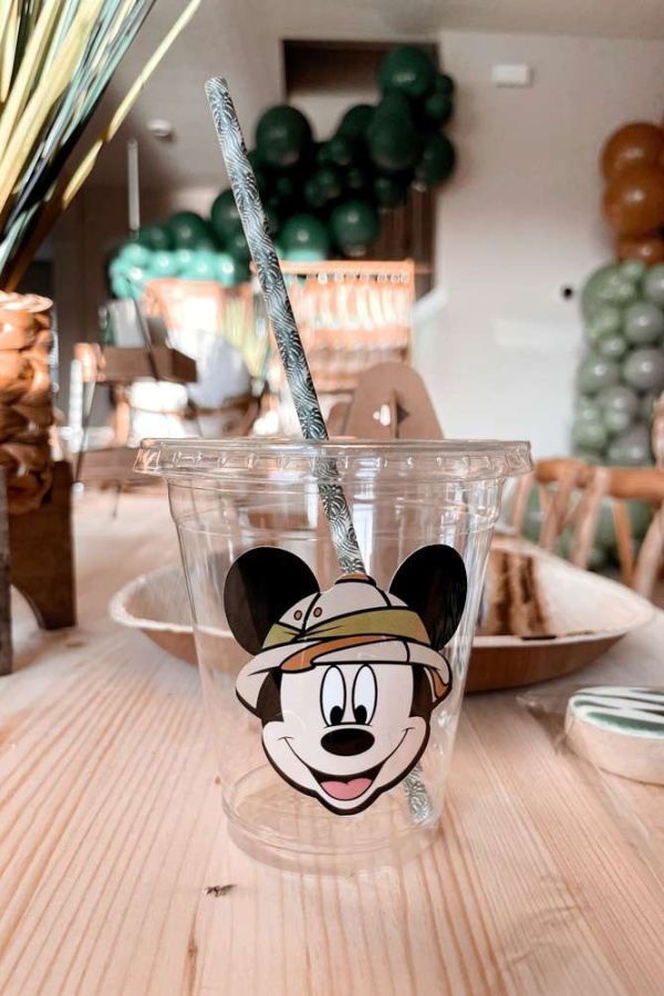 a mickey mouse cup with a straw sticking out of it's head on a wooden table