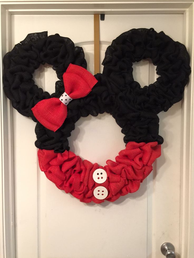 a mickey mouse wreath is hanging on the front door with two buttons attached to it