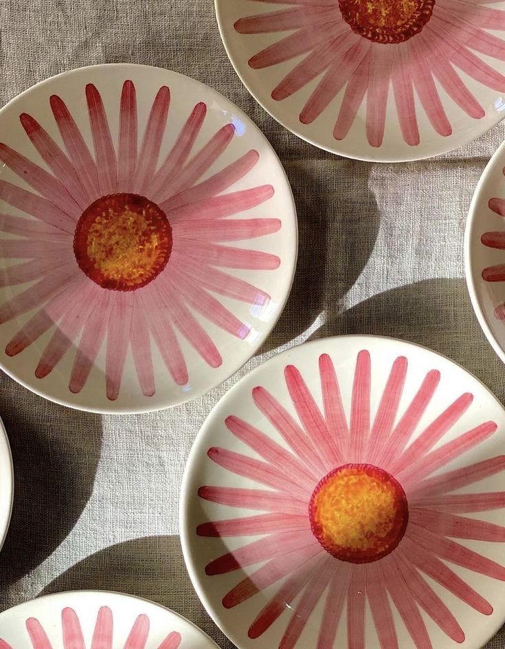 four pink and white plates with flowers painted on the inside are arranged in a pattern