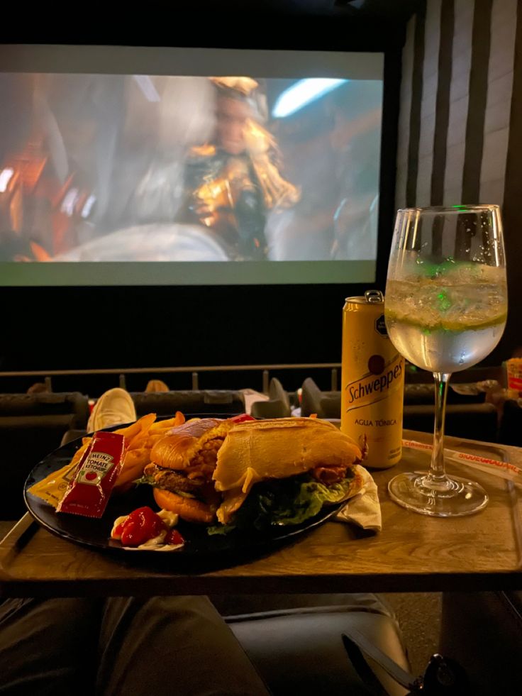 a table with food and drinks on it in front of a movie screen