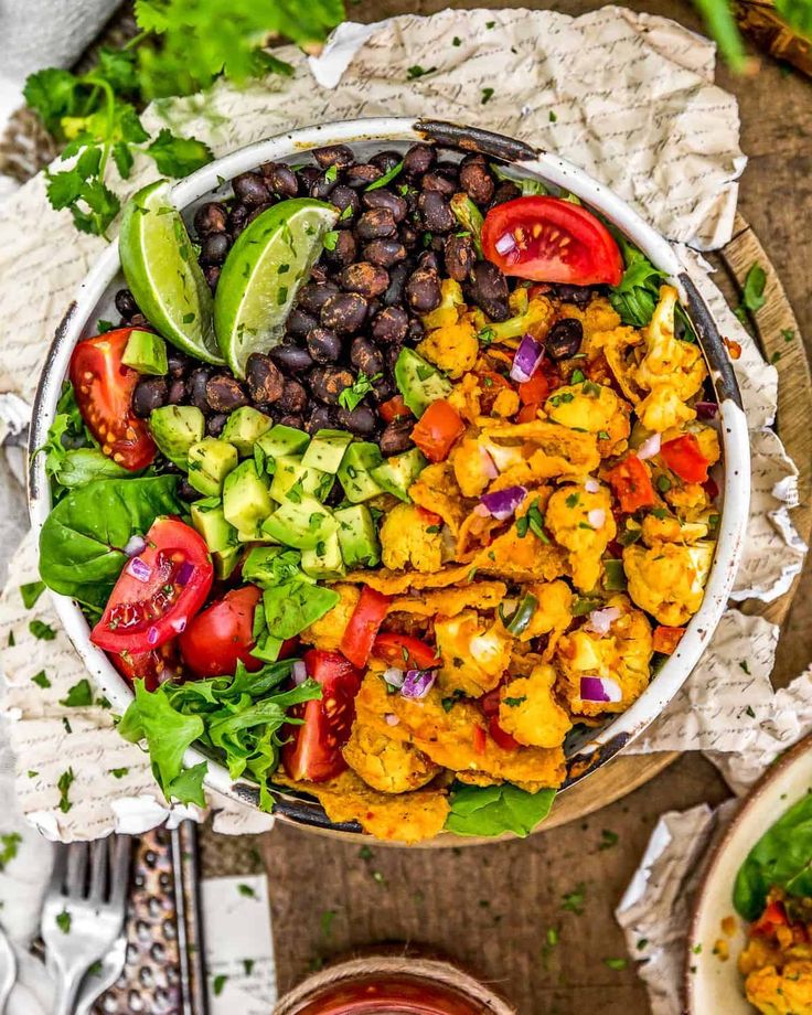 a bowl filled with chicken, black beans, tomatoes and avocado on top of a table