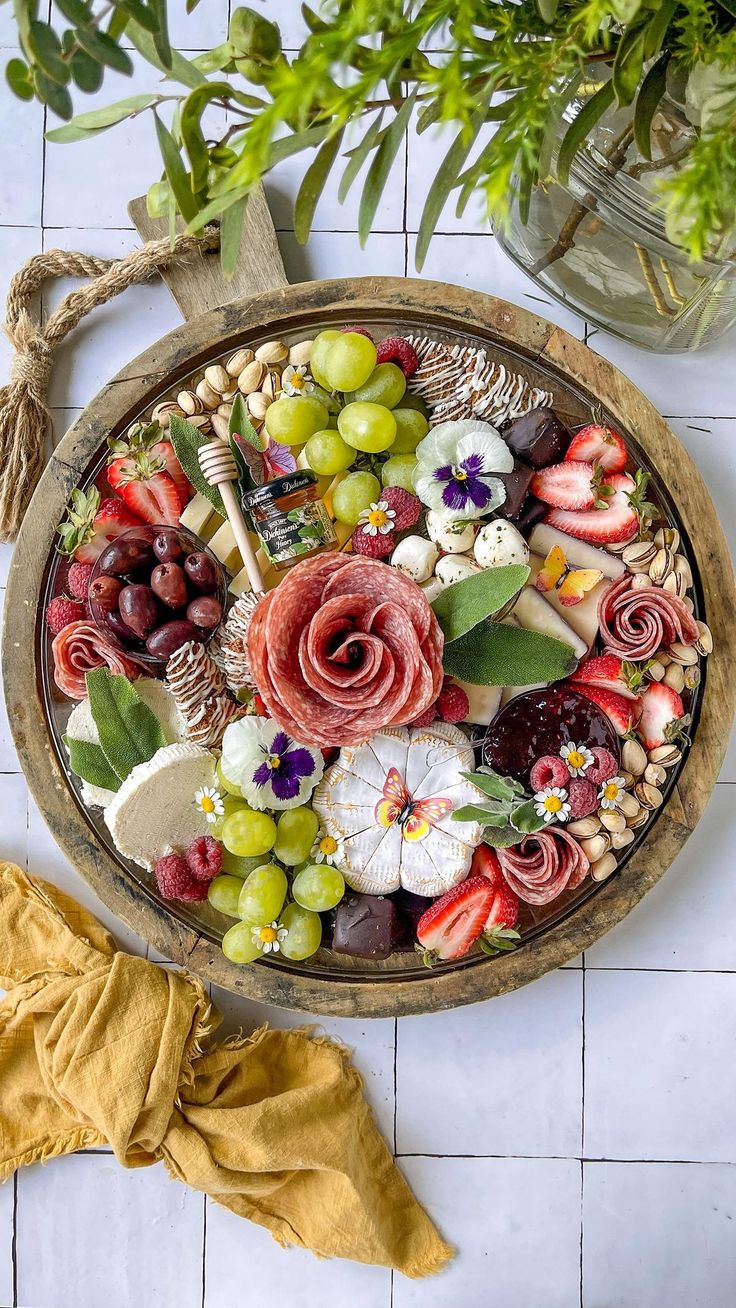 a platter filled with cheese, fruit and flowers